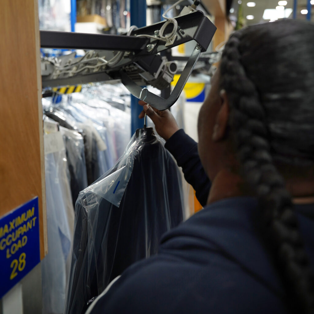 Sudsies team member retrieving a guest’s cleaned garments for pickup